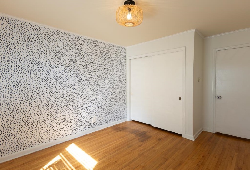 Unfurnished bedroom featuring a closet, baseboards, crown molding, and light wood-type flooring