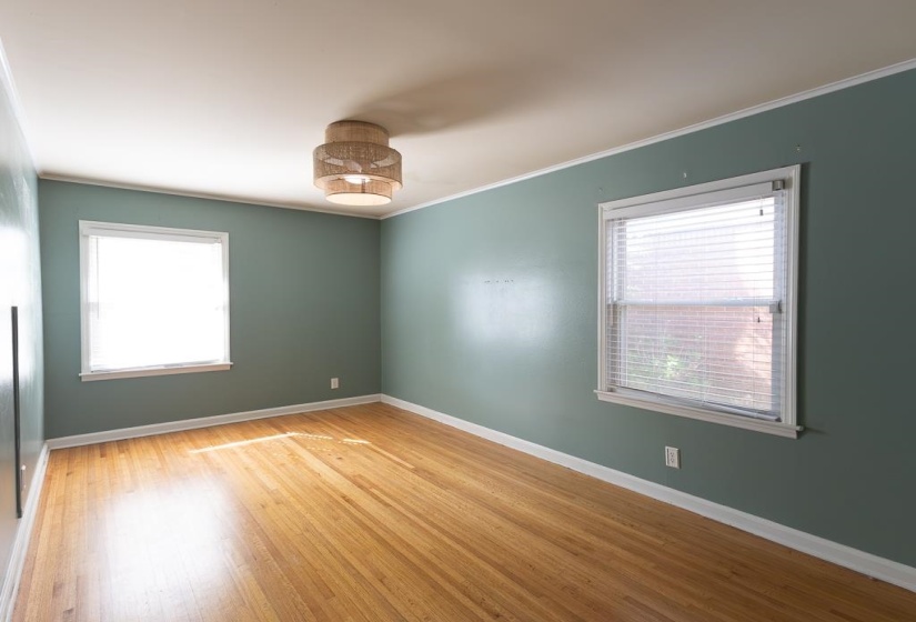 Spare room featuring baseboards, crown molding, and wood finished floors