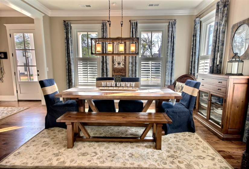 Dining space with visible vents, wood finished floors, ornamental molding, and a healthy amount of sunlight