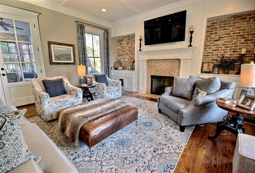 Living area featuring ceiling fan, wood finished floors, a premium fireplace, and crown molding