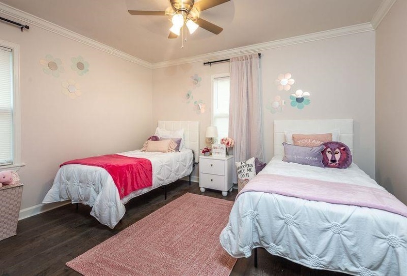 Bedroom with baseboards, crown molding, ceiling fan, and dark wood-style flooring