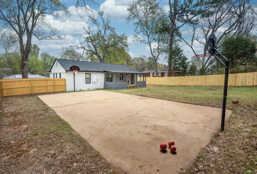 Rear view of property with basketball hoop and driveway