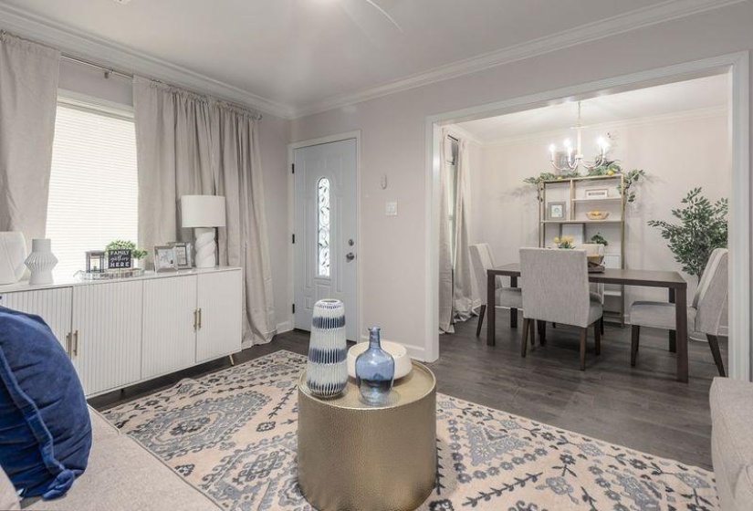 Living area featuring baseboards, crown molding, wood finished floors, and a chandelier