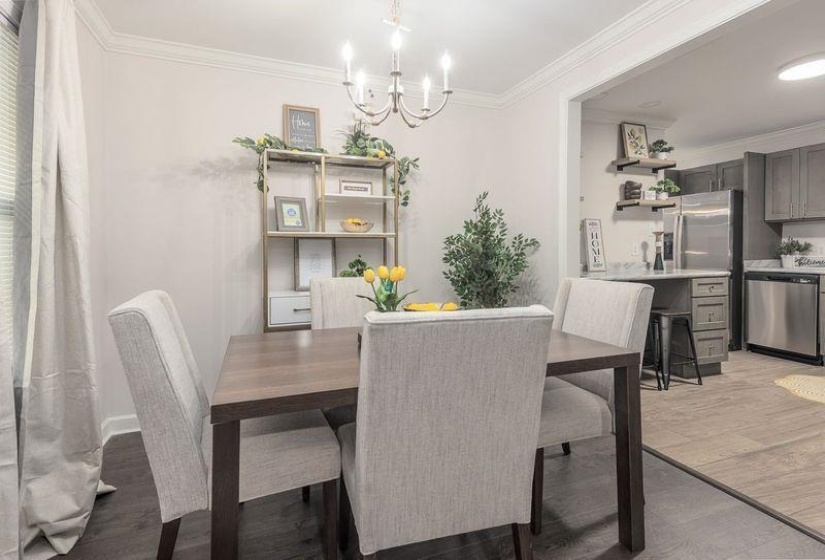 Dining room with a notable chandelier, crown molding, and light wood-style flooring