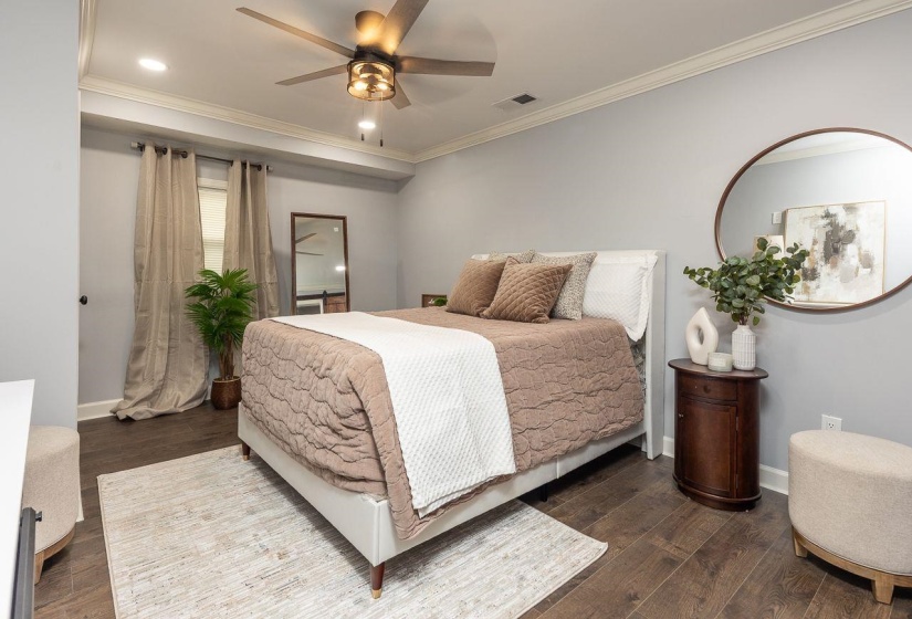 Bedroom with dark wood-style flooring, ornamental molding, baseboards, and visible vents