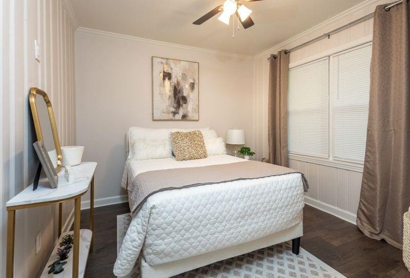 Bedroom featuring a ceiling fan, crown molding, baseboards, and wood finished floors