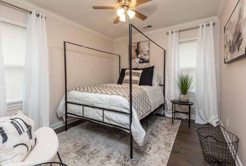 Bedroom featuring baseboards, visible vents, crown molding, and wood finished floors