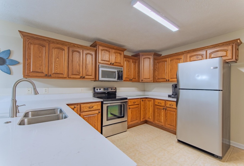 Kitchen featuring light countertops, a sink, brown cabinetry, and appliances with stainless steel finishes