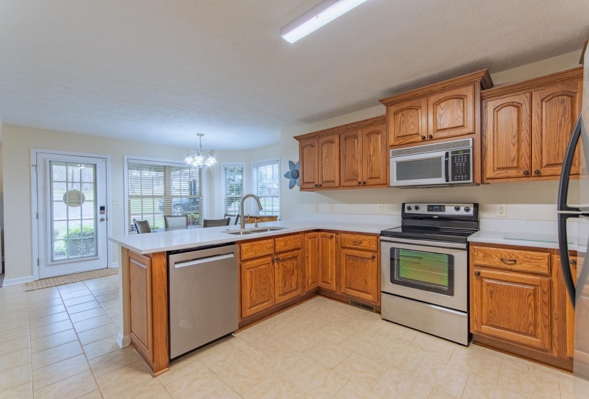 Kitchen with brown cabinets, a sink, a notable chandelier, and appliances with stainless steel finishes