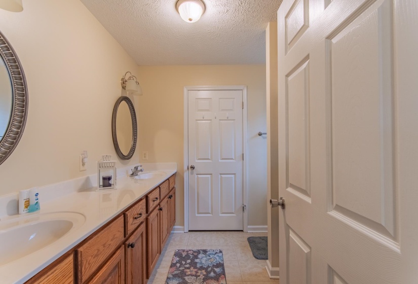Bathroom with double vanity, tile patterned flooring, a sink, and a textured ceiling