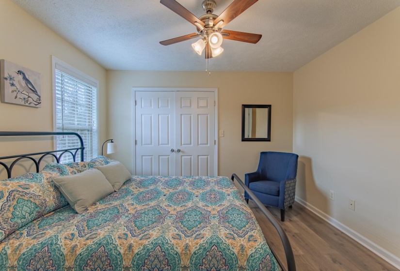 Bedroom with a closet, a textured ceiling, baseboards, wood finished floors, and a ceiling fan