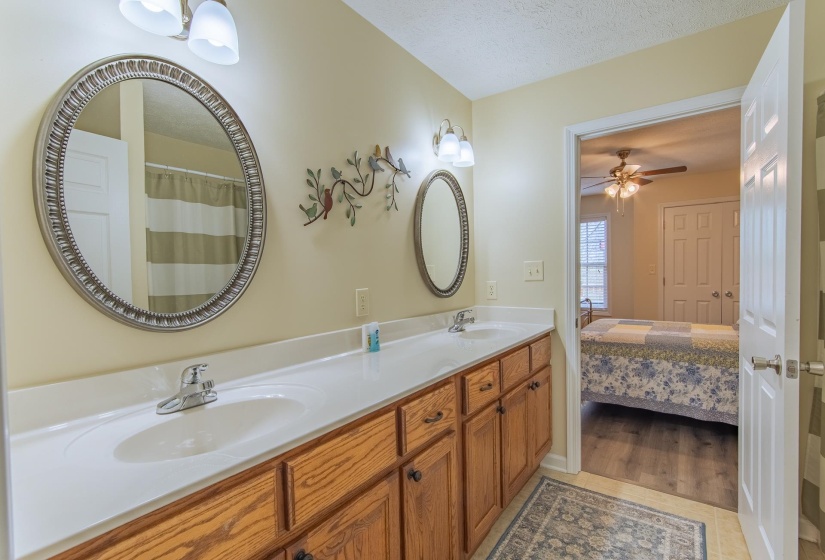 Ensuite bathroom featuring double vanity, tile patterned flooring, a sink, and a textured ceiling
