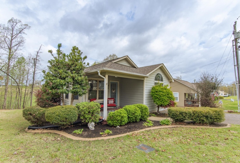 View of property exterior featuring a porch, roof with shingles, and a lawn