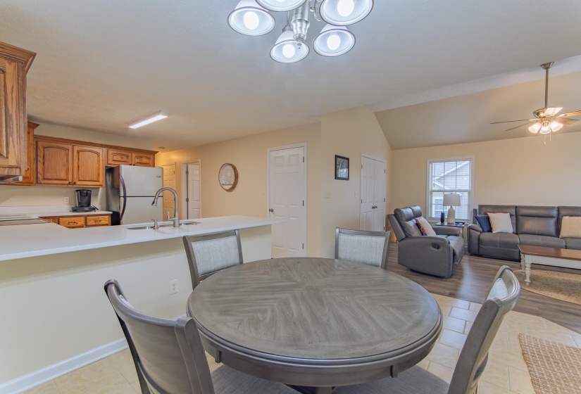 Dining area with light tile patterned floors, vaulted ceiling, and ceiling fan with notable chandelier
