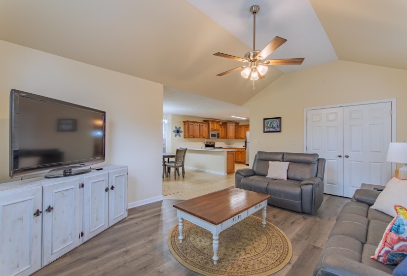 Living area with baseboards, ceiling fan, vaulted ceiling, and light wood-style floors