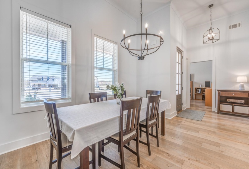 Dining area featuring a notable chandelier, baseboards, light wood finished floors, and visible vents