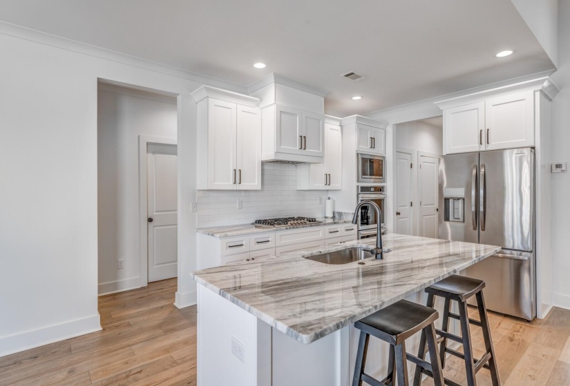 Kitchen with a kitchen breakfast bar, stainless steel appliances, decorative backsplash, a sink, and visible vents