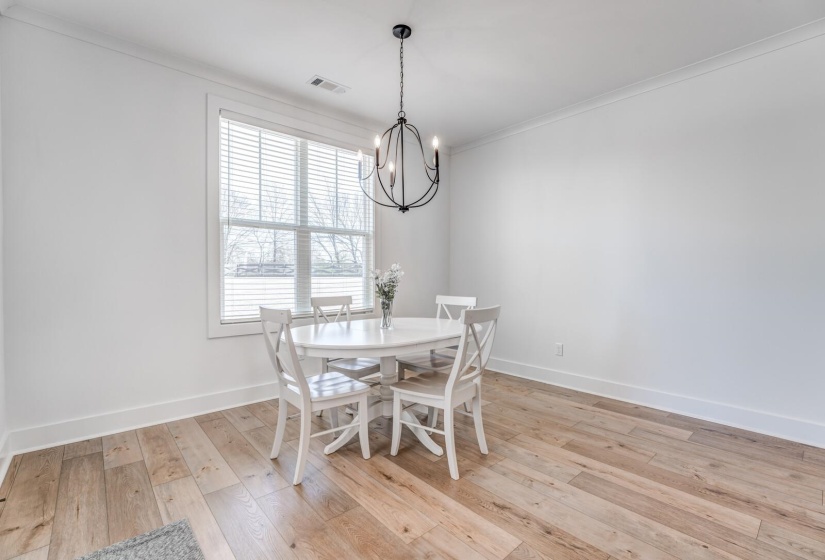 Dining room featuring crown molding, a chandelier, light wood-type flooring, baseboards, and visible vents