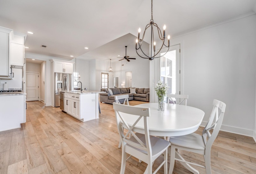 Dining area featuring light wood-style flooring, ceiling fan with notable chandelier, baseboards, and recessed lighting