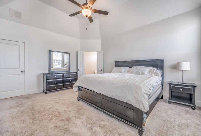 Bedroom with high vaulted ceiling, carpet flooring, a ceiling fan, baseboards, and visible vents