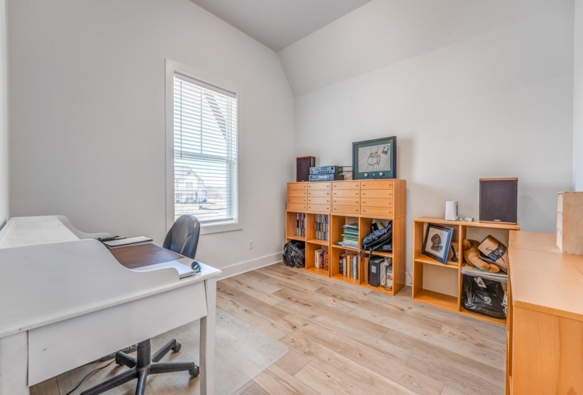 Home office with baseboards, light wood-type flooring, and lofted ceiling