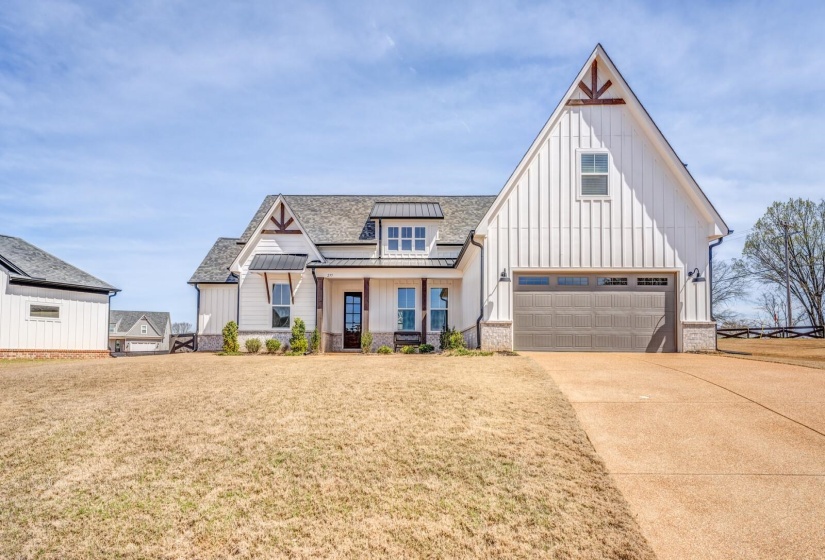 Modern inspired farmhouse with a garage, concrete driveway, a front yard, a standing seam roof, and board and batten siding