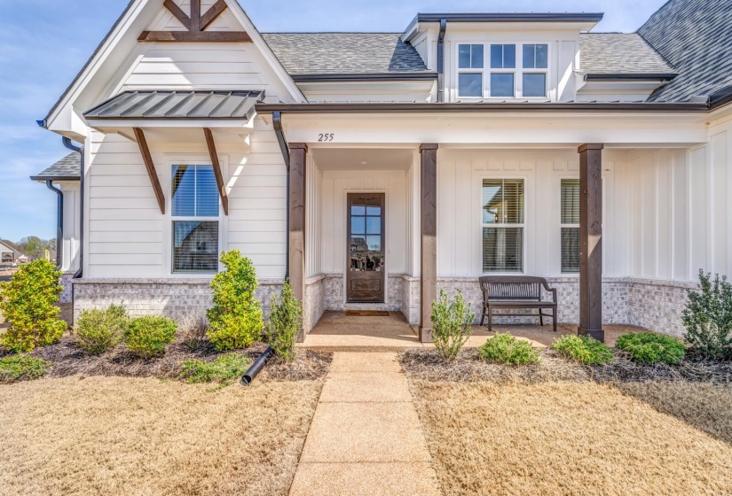 Entrance to property featuring covered porch, stone siding, board and batten siding, and roof with shingles