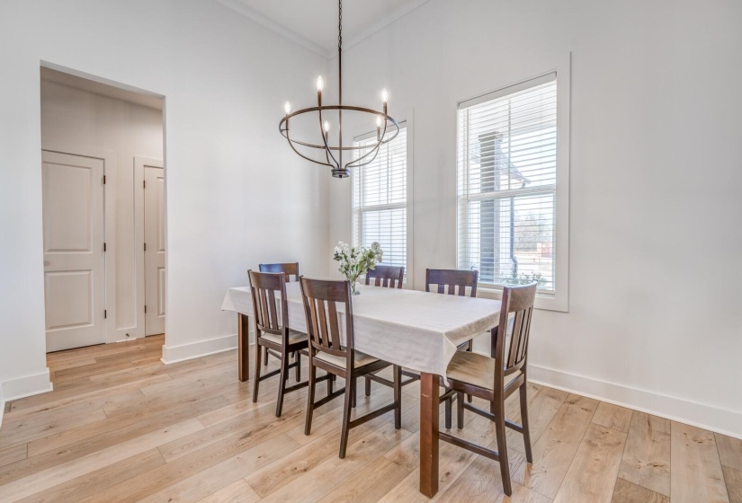 Dining room with baseboards, ornamental molding, a notable chandelier, and light wood finished floors