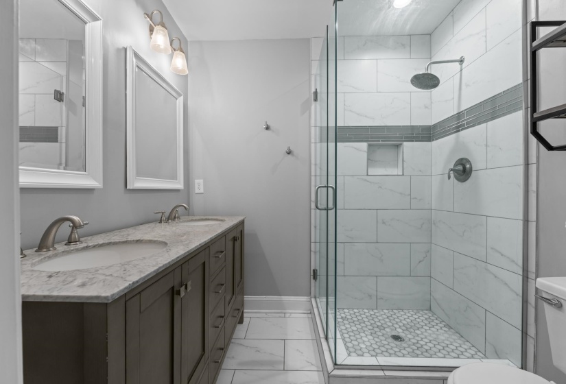 Ensuite bathroom features double vanities, frameless shower, nicely updated