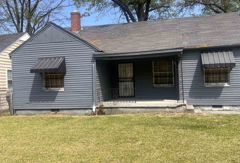 Rear view of property with a chimney, a lawn, a porch, and a shingled roof