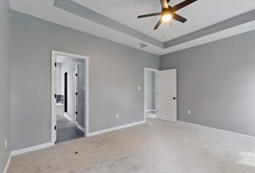 Unfurnished bedroom with baseboards, carpet floors, and a raised ceiling