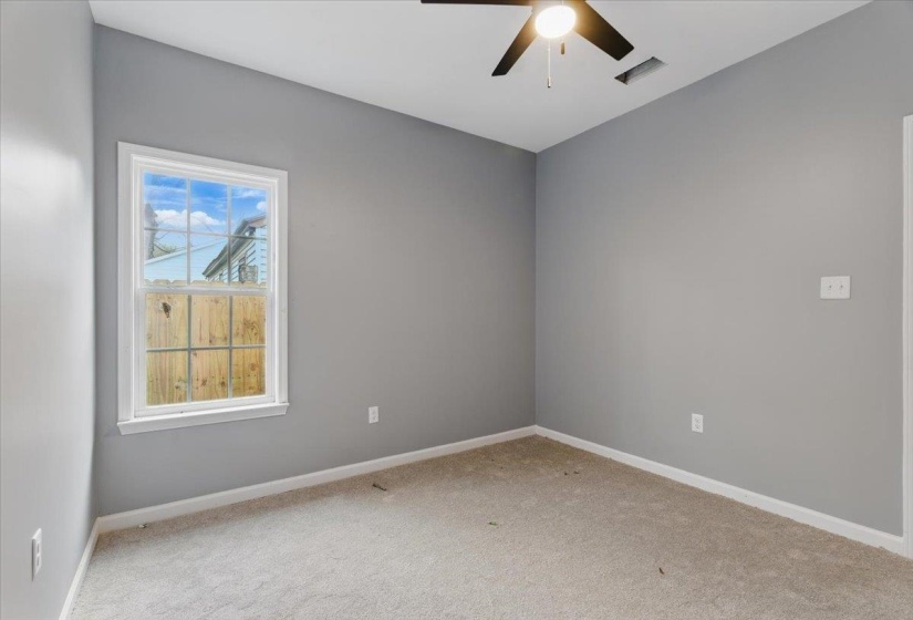 Empty room with baseboards, visible vents, carpet floors, and a ceiling fan
