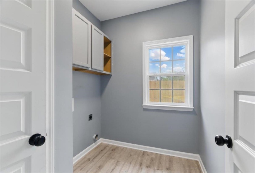 Laundry area featuring cabinet space, hookup for an electric dryer, baseboards, and light wood-type flooring