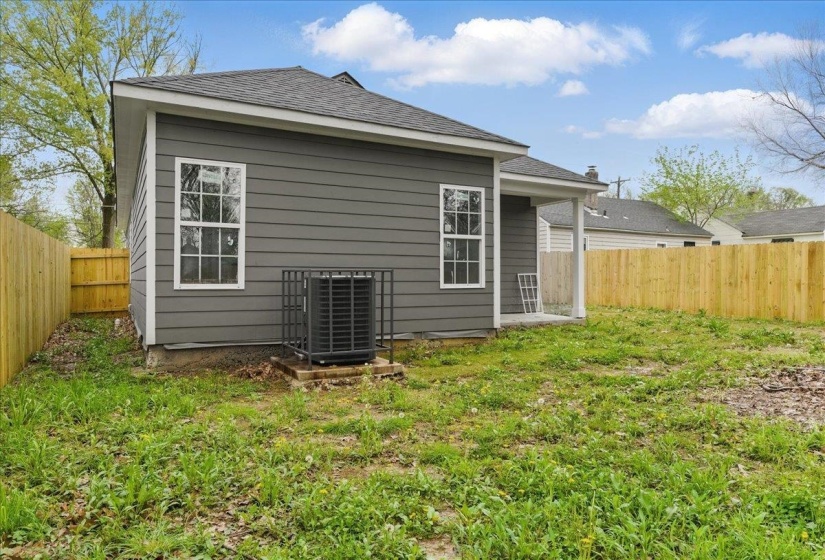 Back of house featuring a fenced backyard, cooling unit, and a yard