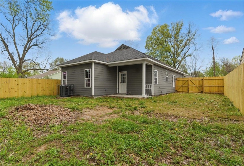 Back of property with cooling unit, a fenced backyard, a yard, and a patio area