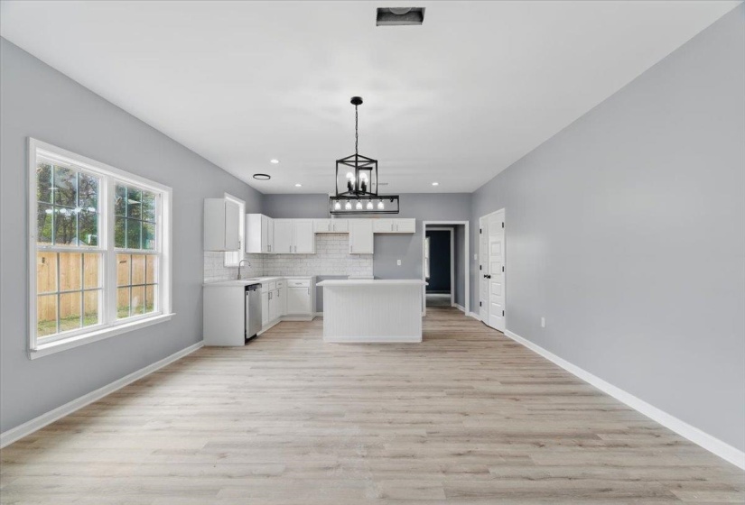Kitchen with a sink, tasteful backsplash, dishwasher, white cabinets, and an inviting chandelier