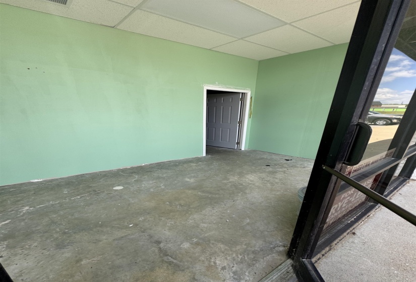 Empty room with unfinished concrete floors and a paneled ceiling