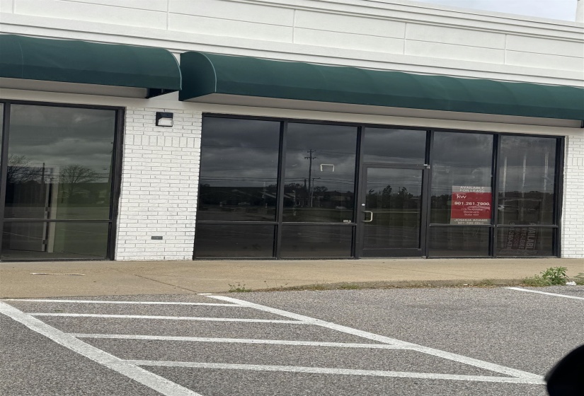 Doorway to property with brick siding and uncovered parking