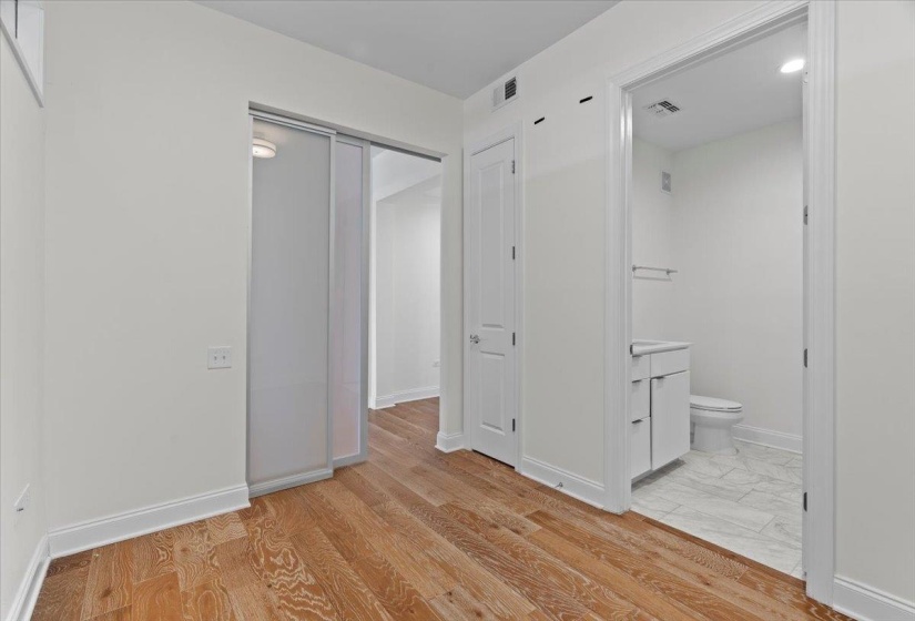 Unfurnished bedroom with ensuite bath, visible vents, and baseboards