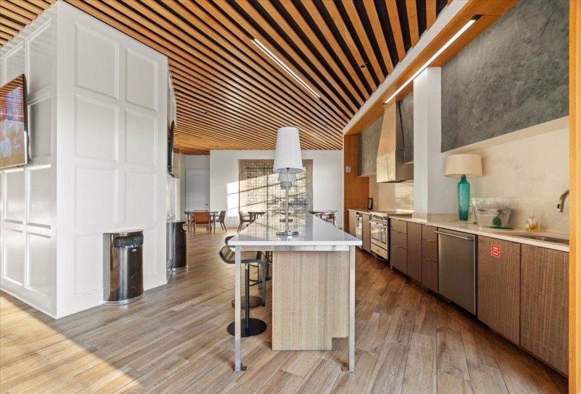 Kitchen with light wood-style floors, custom exhaust hood, appliances with stainless steel finishes, light countertops, and a sink