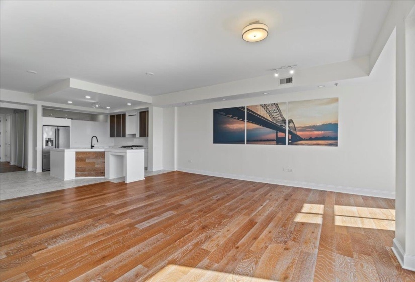 Unfurnished living room featuring baseboards, light wood-type flooring, a sink, and visible vents
