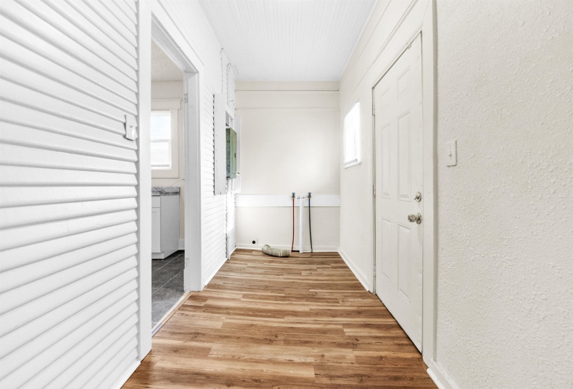 Hall with light wood-style floors, a textured wall, and plenty of natural light