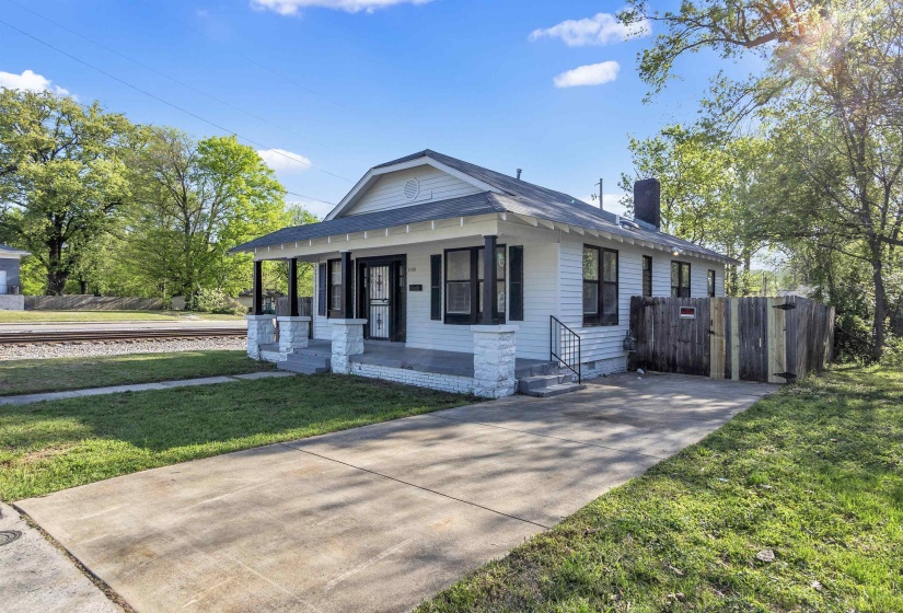 Bungalow with a chimney, covered porch, driveway, and a front lawn