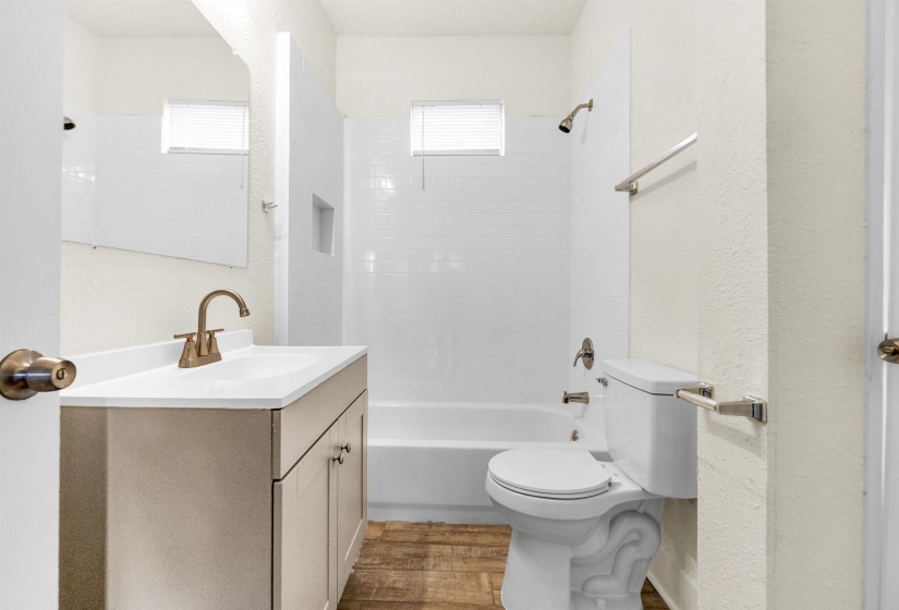 Full bathroom with vanity, toilet, shower / bath combination, wood finished floors, and a textured wall