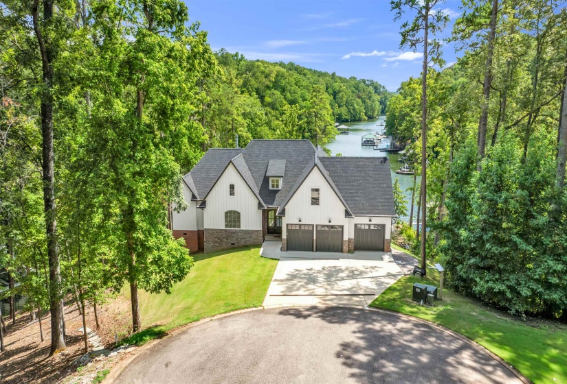 Modern farmhouse style home featuring driveway, roof with shingles, a water view, a front lawn, and brick siding