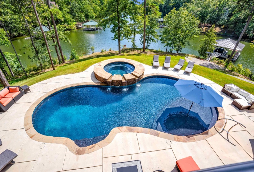 View of pool with a yard, a patio, a water view, and a pool with connected hot tub