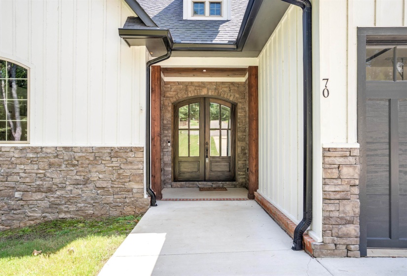 Entrance to property featuring stone siding, a shingled roof, and french doors