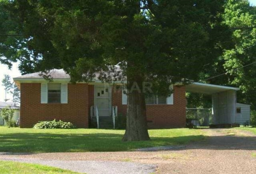 View of front facade featuring a front lawn and a carport
