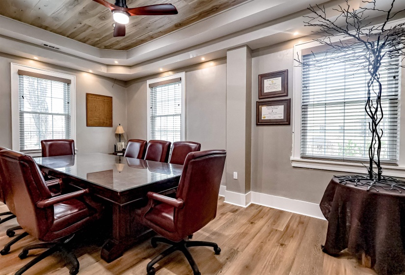Dining area featuring a ceiling fan, a wealth of natural light, light wood-style flooring, baseboards, and a raised ceiling