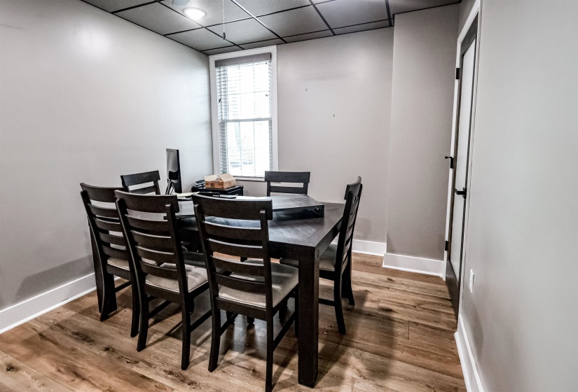 Dining area featuring wood finished floors, baseboards, and a drop ceiling